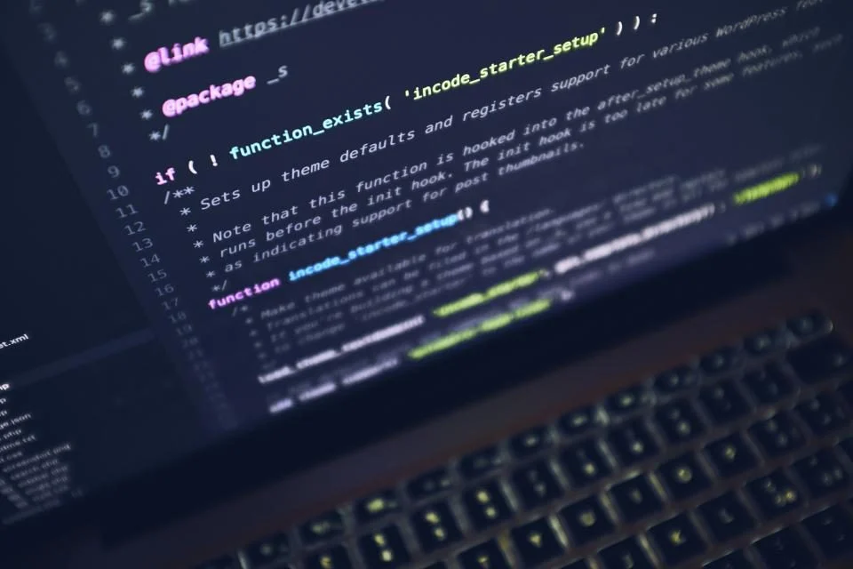 Código colorido na tela de um notebook, em ambiente escuro