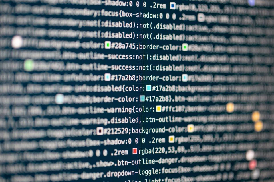 Tela de computador com linhas de código em close, a maior parte desfocada