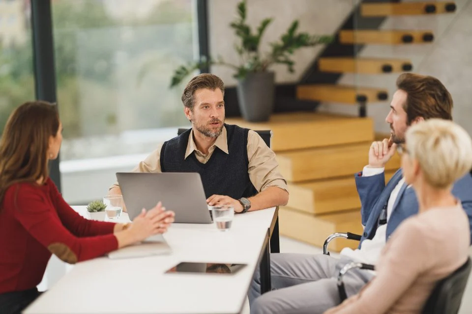 Equipe reunida em volta de uma mesa com notebooks, conversando