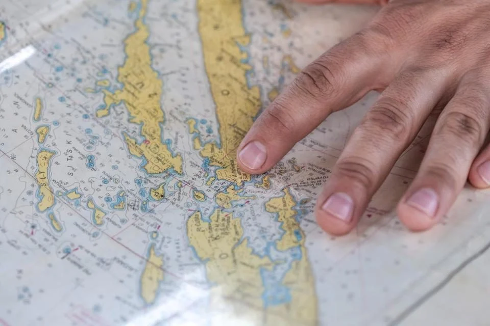 Mão apontando um trecho de um mapa impresso