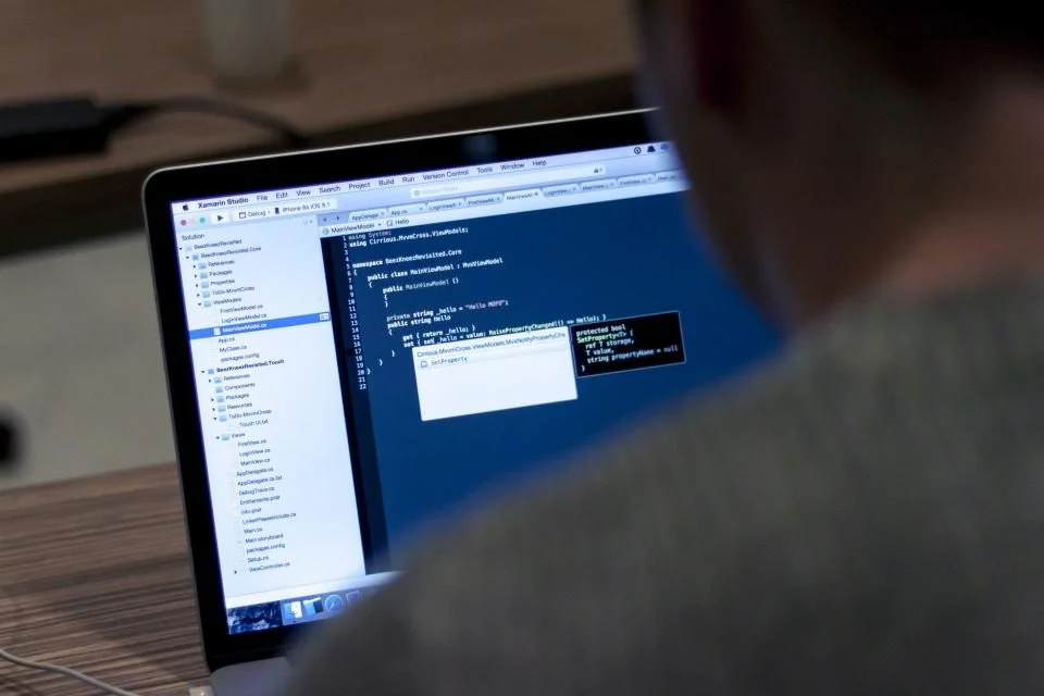 Pessoa programando num notebook com código na tela