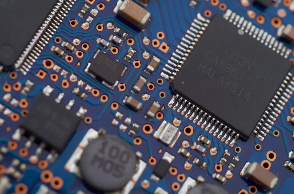 Placa de circuito azul com um chip e componentes eletrônicos em close
